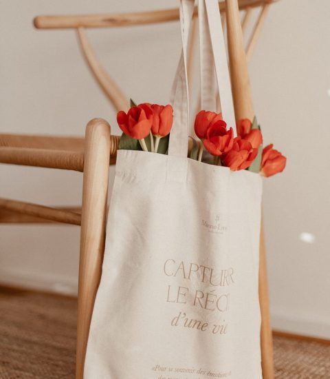 Un tote bag suspendu à une chaise en bois avec des tulipes à l'intérieur